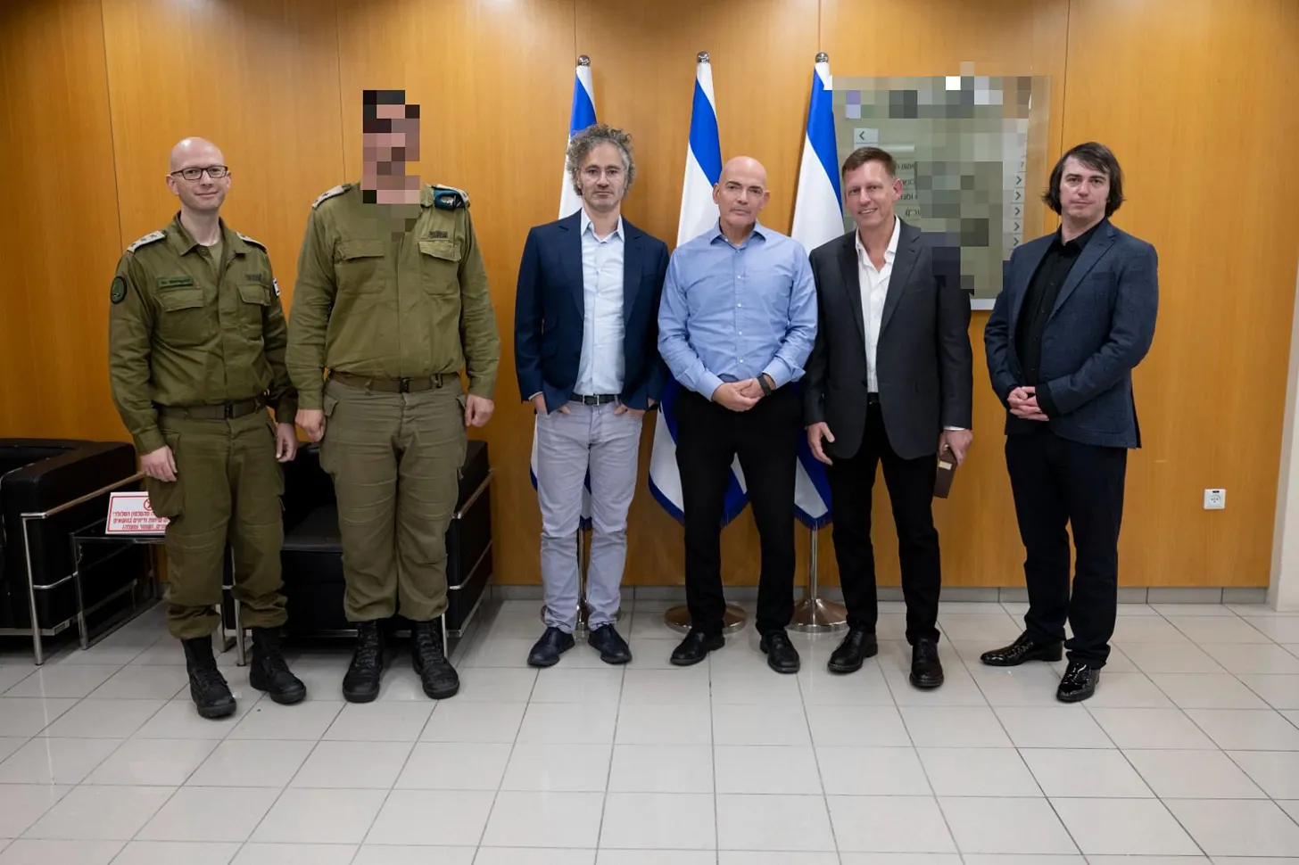 Group photo of military officers in olive uniforms alongside corporate executives including Peter Thiel standing in front of Israeli flags.